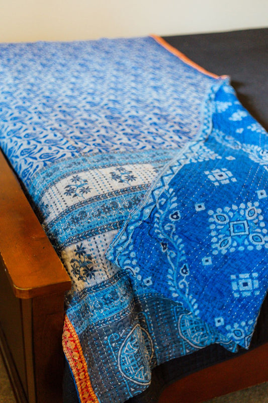 a reversible, quilted blue kantha throw blanket on a bed