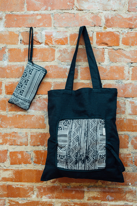 Charcoal foldable tote bag with white pattern against a brick wall
