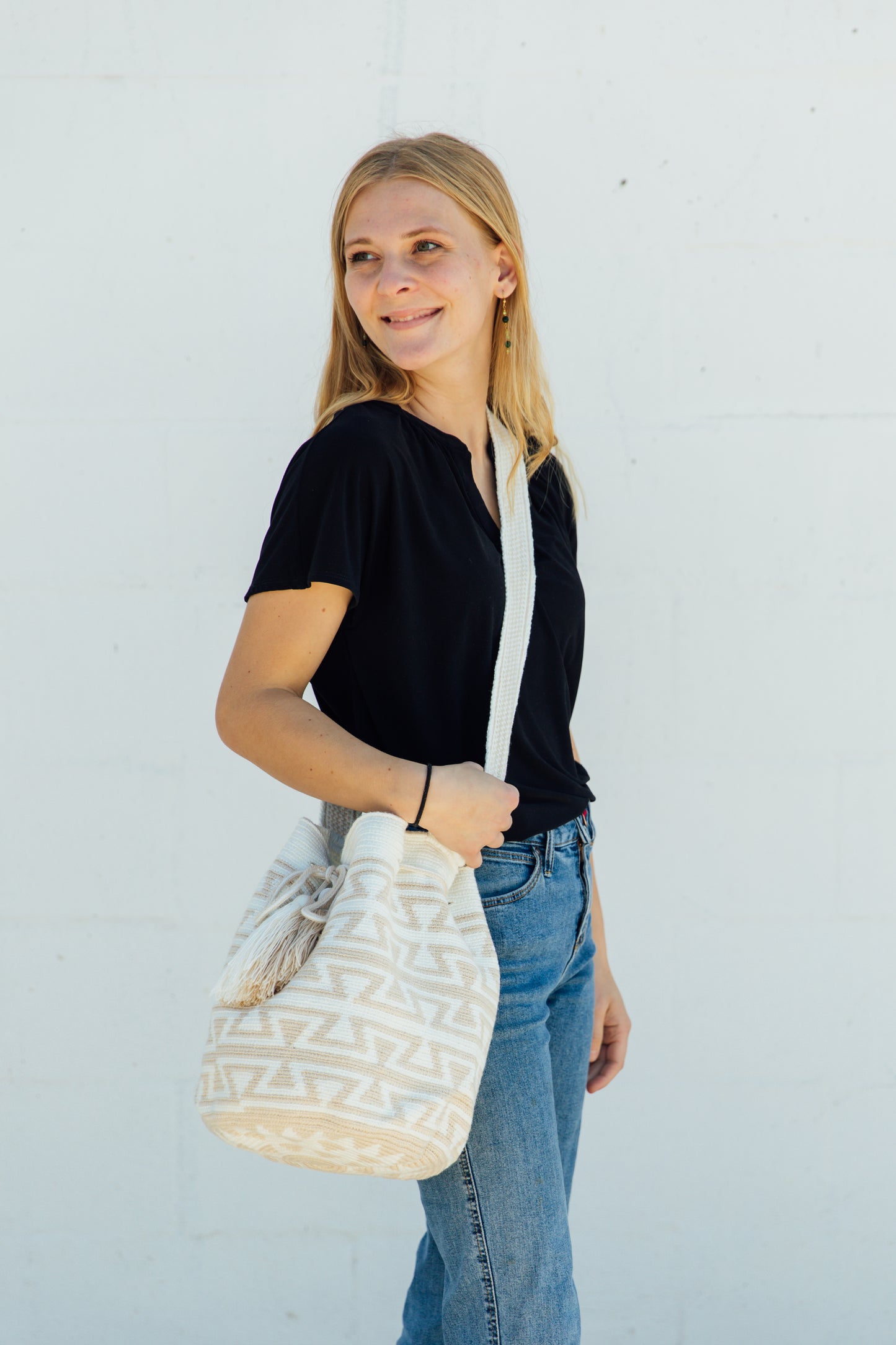 A model wearing a white and tan wayuu bag as a crossbody