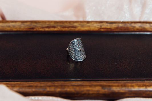 A sterling silver ring with a textured surface, displayed on a wooden surface.