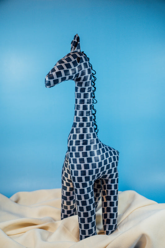 A handcrafted giraffe made from vibrant African fabric, displayed against a blue background.