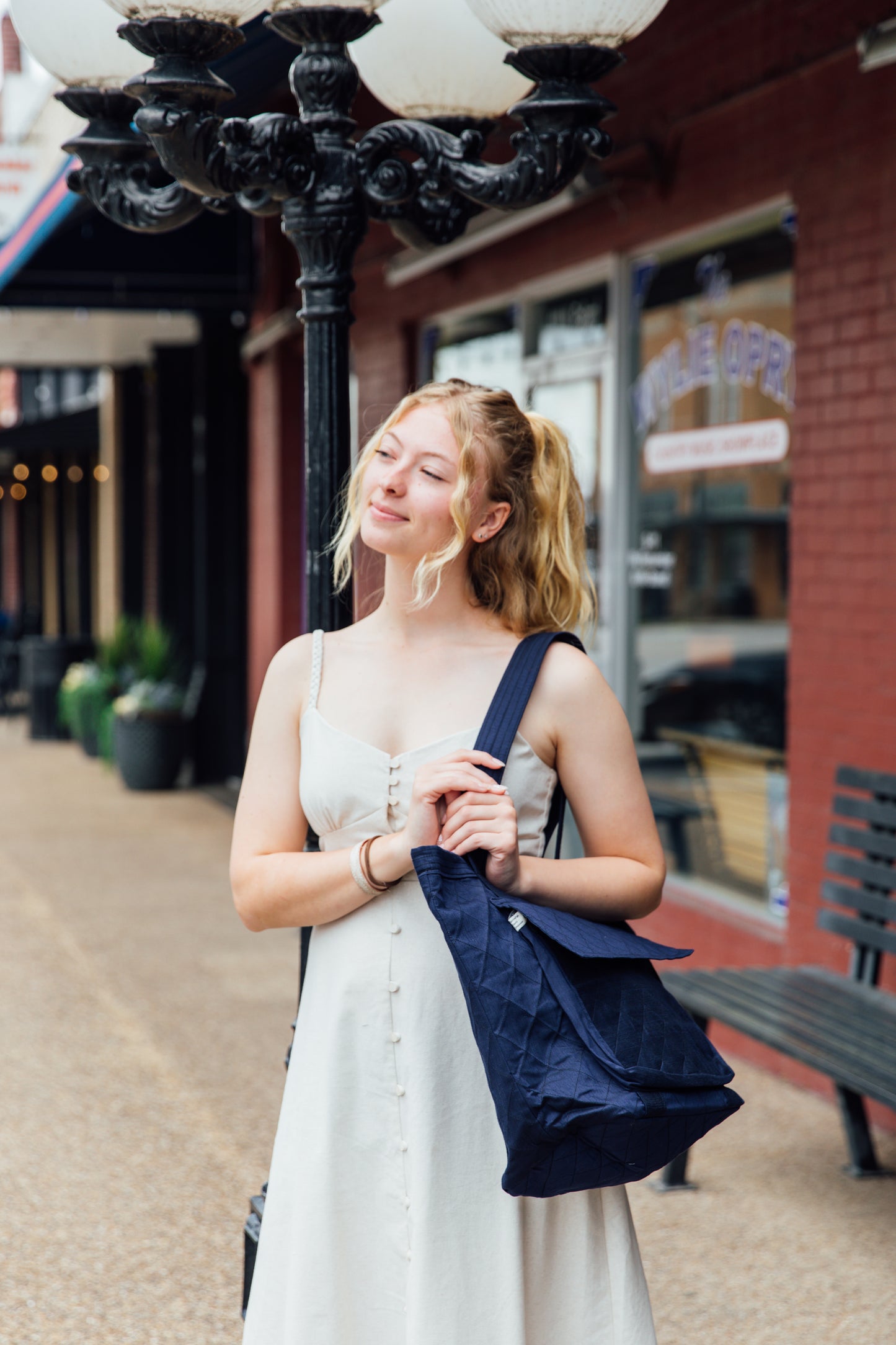 A woman holding an blue indian tote bag from Hope's Gate