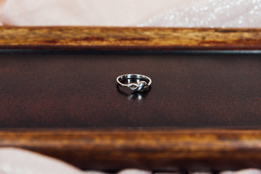 A silver ring with a sleek design displayed on a wooden surface.
