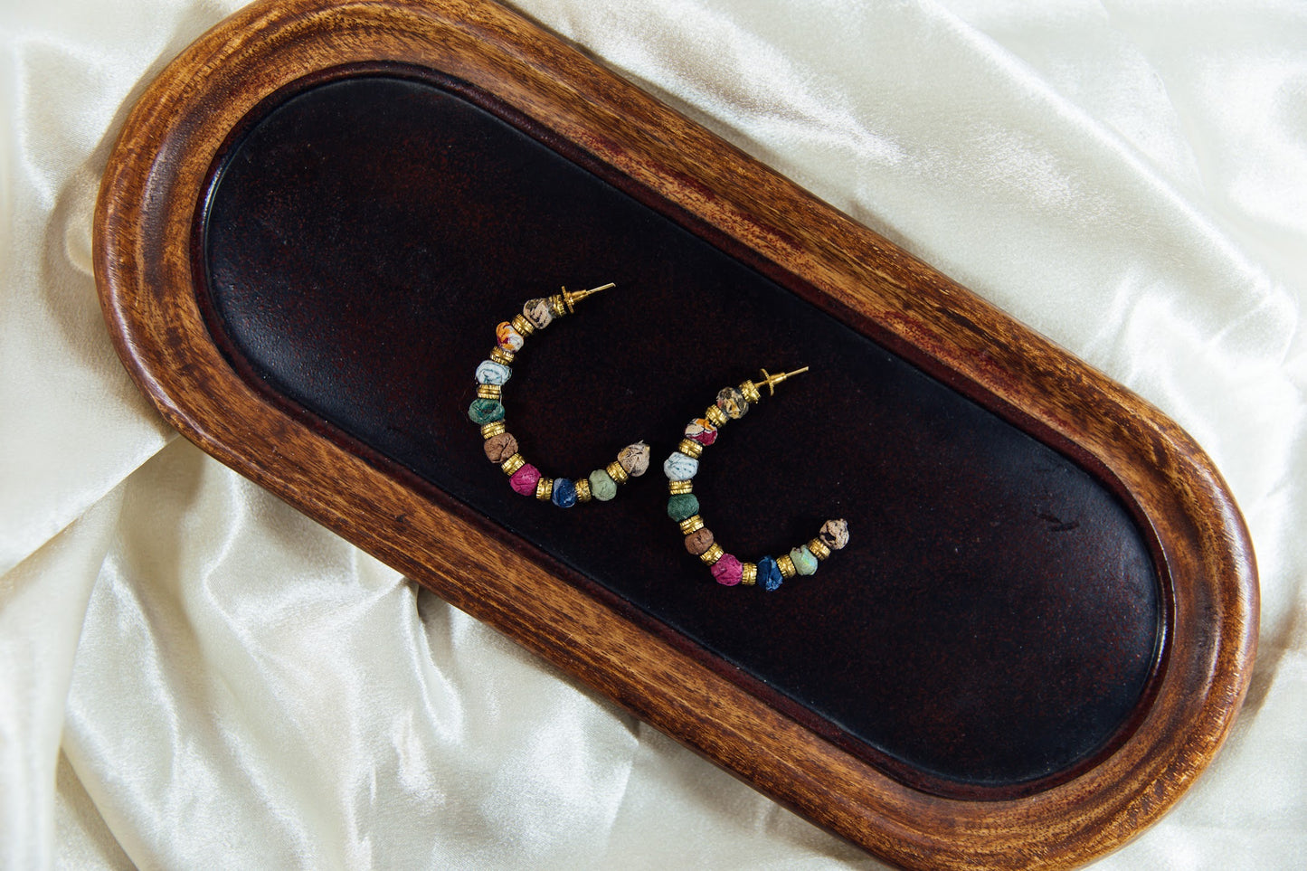 Large hoop earring with multicolored fabric beads.