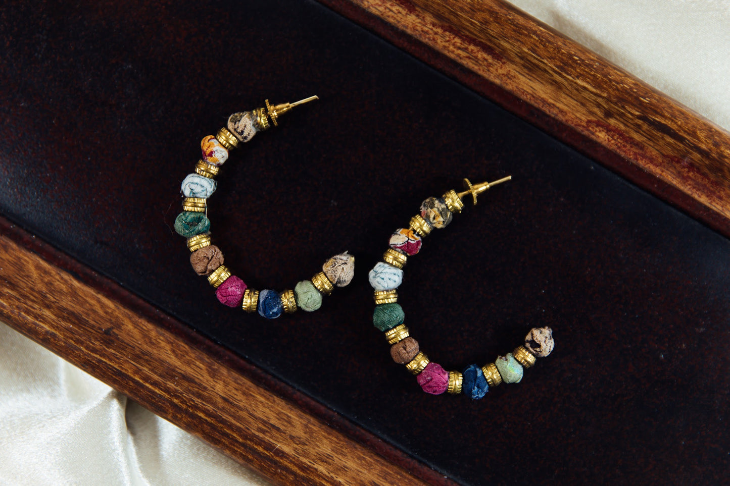 Large hoop earring with multicolored fabric beads.