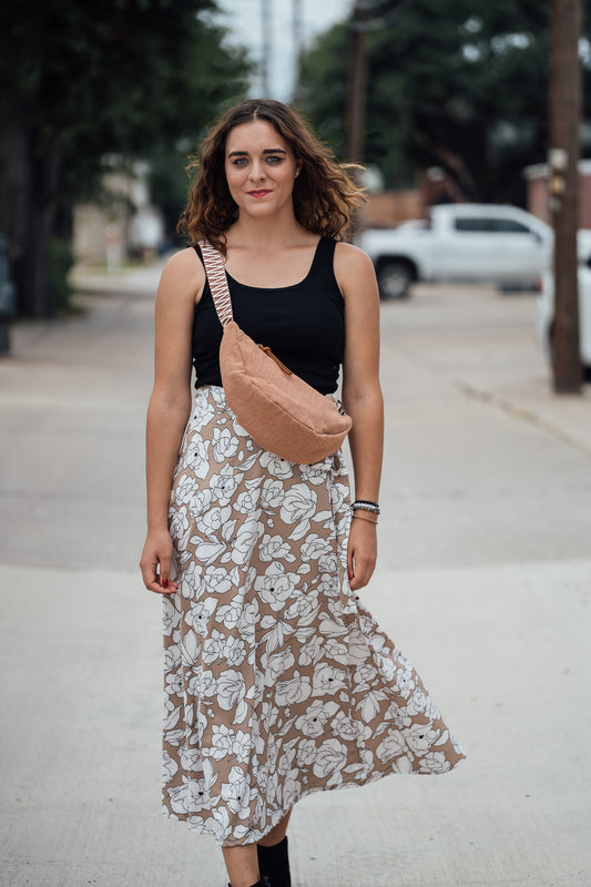 Woman wearing a black top and floral skirt with the Sienna Thai Dumpling bag on a street.