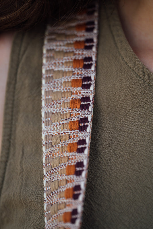 Close-up of a patterned strap on a green garment