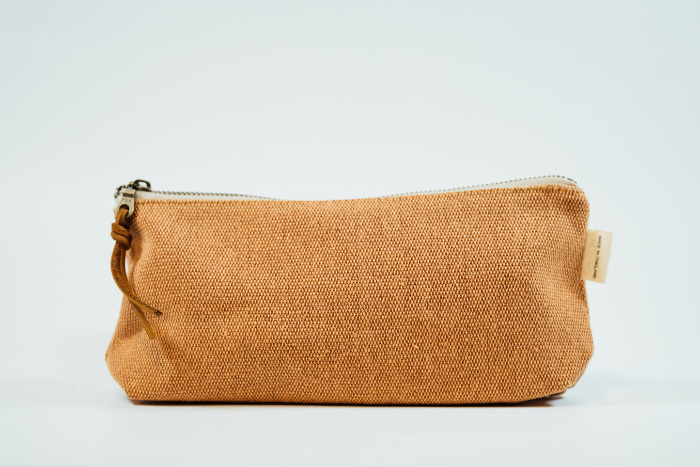 A copper fabric pencil case with a metal zipper and a leather tassel, against a white background.