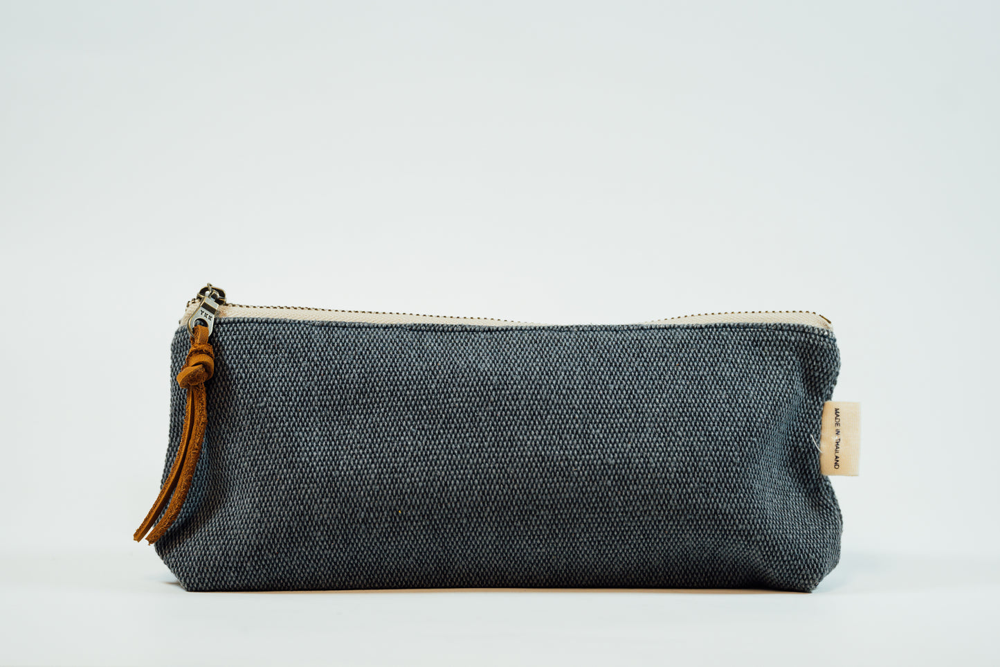 A navy fabric pencil case with a metal zipper and a leather tassel, against a white background.