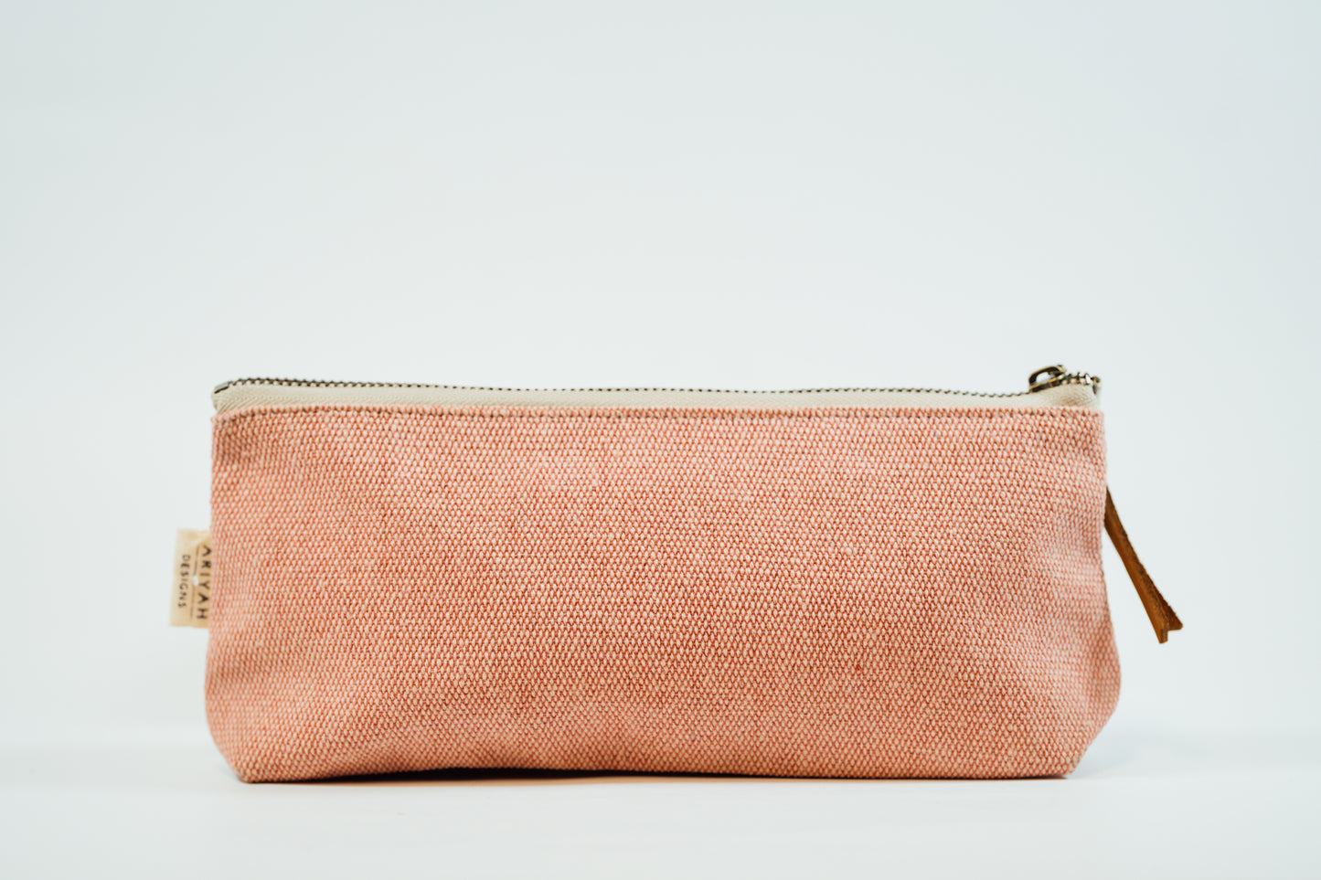 A pink fabric pencil case with a metal zipper and a leather tassel, against a white background.