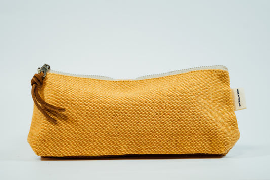 A yellow fabric pencil case with a metal zipper and a leather tassel, against a white background.