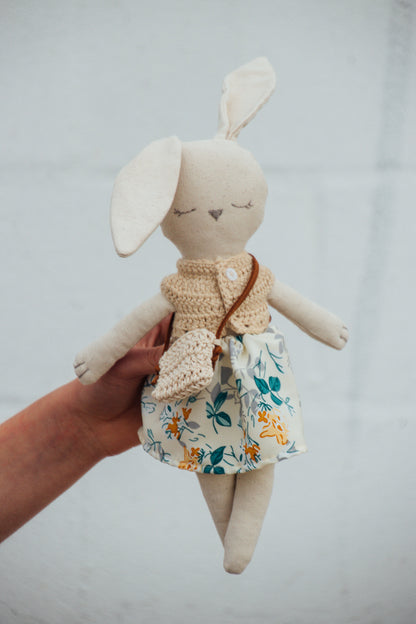 A Bunny Stuffed animal wearing a tan and green floral skirt and tan crocheted top from Hope's Gate