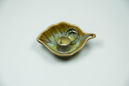 Ceramic leaf-shaped dish with silver rings on a white background