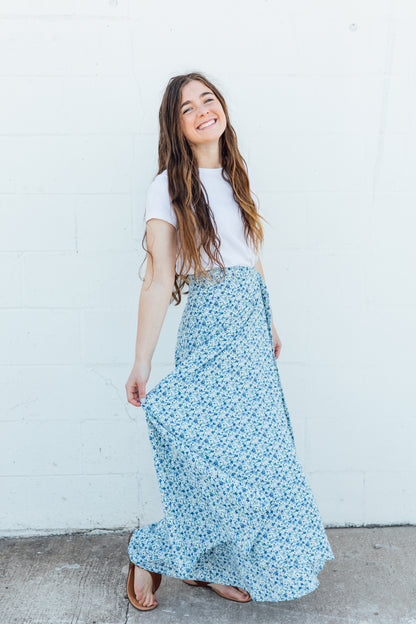 A woman wearing a blue floral maxi wrap skirts.