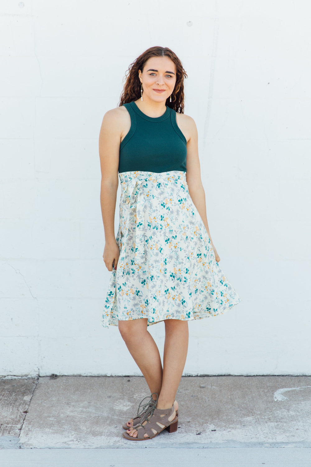 A woman wearing a cream colored midi wrap skirt with green and gold accents.