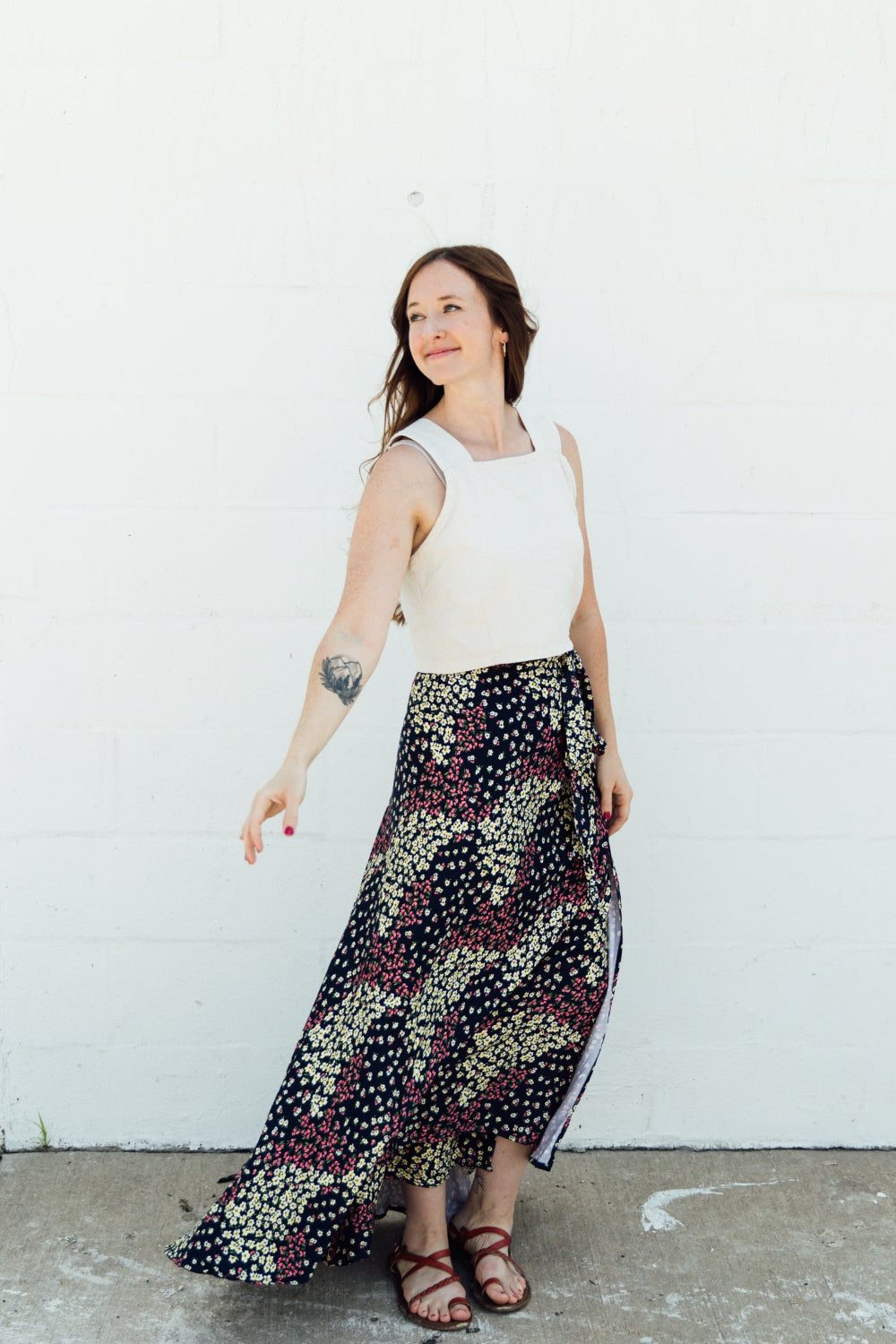 A woman wearing a navy maxi wrap skirt with pink and yellow floral accents