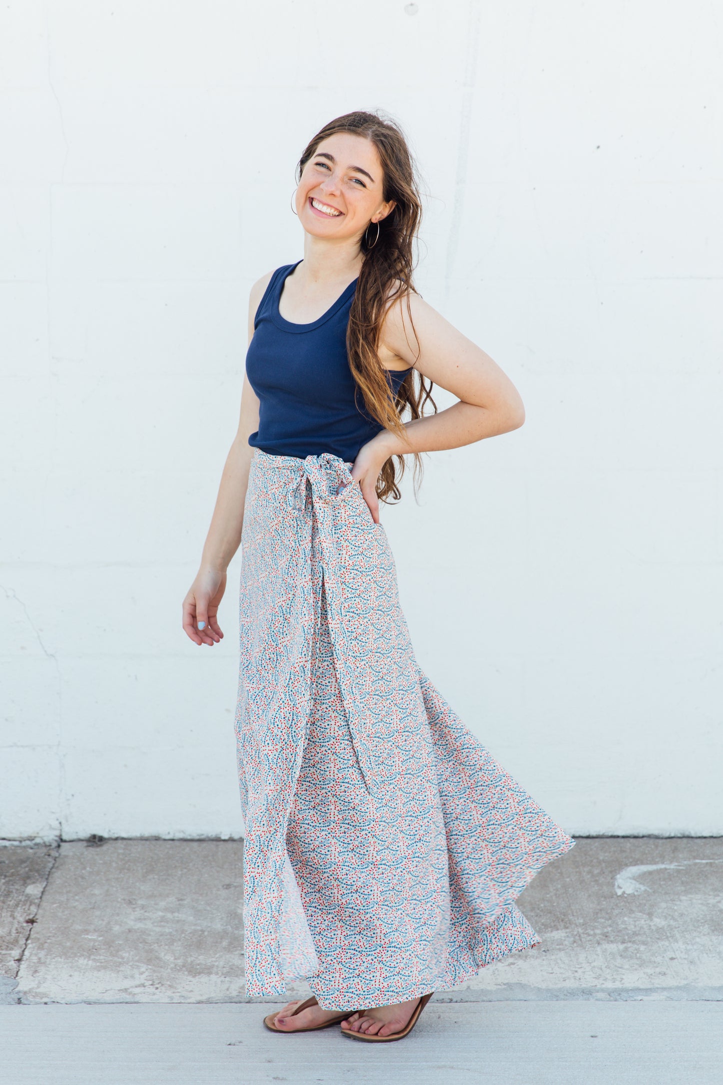 A woman wearing a white maxi wrap skirt with blue and red floral accents.