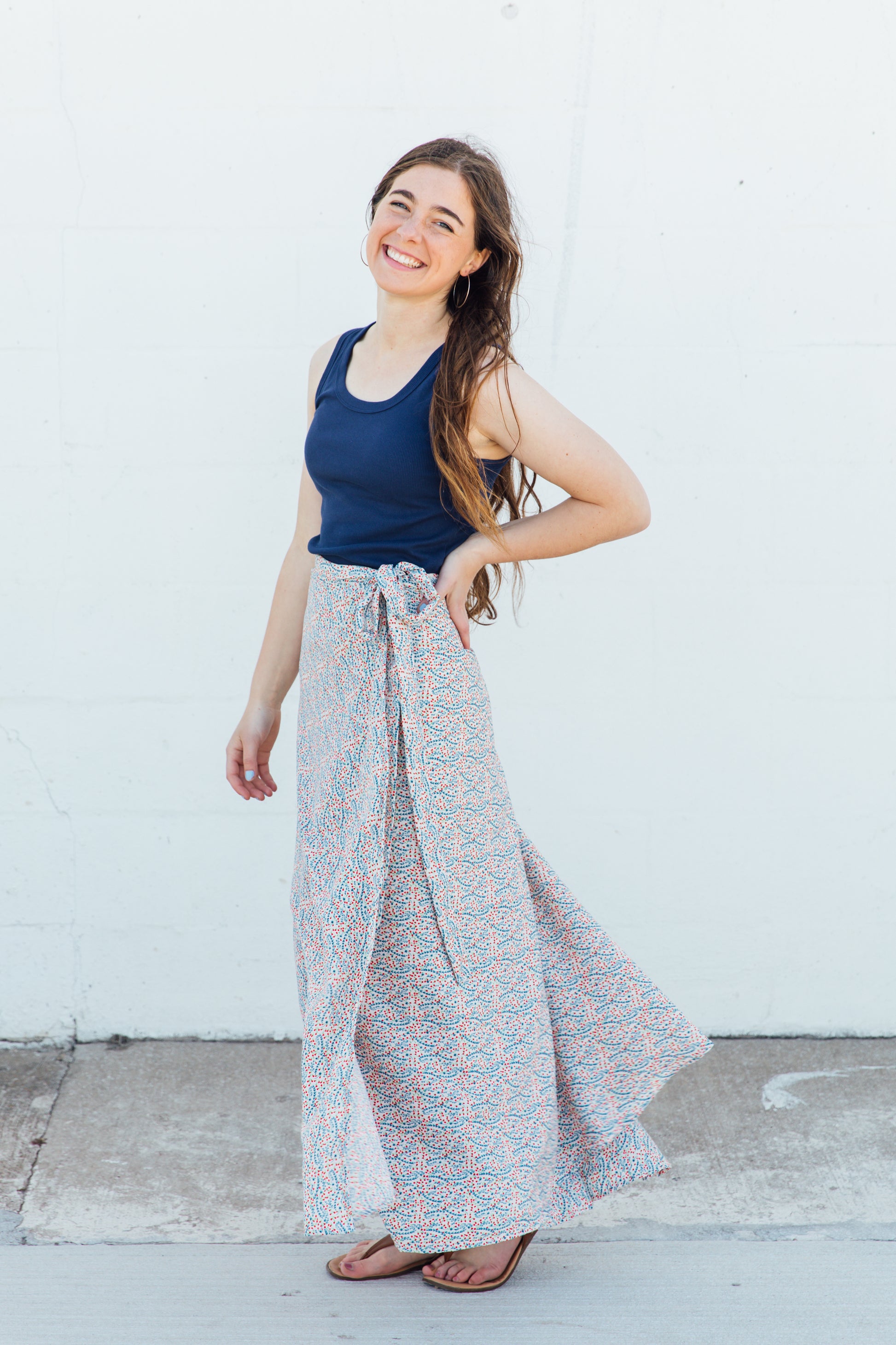 A woman wearing a white maxi wrap skirt with blue and red floral accents.