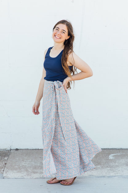 A woman wearing a white maxi wrap skirt with blue and red floral accents.