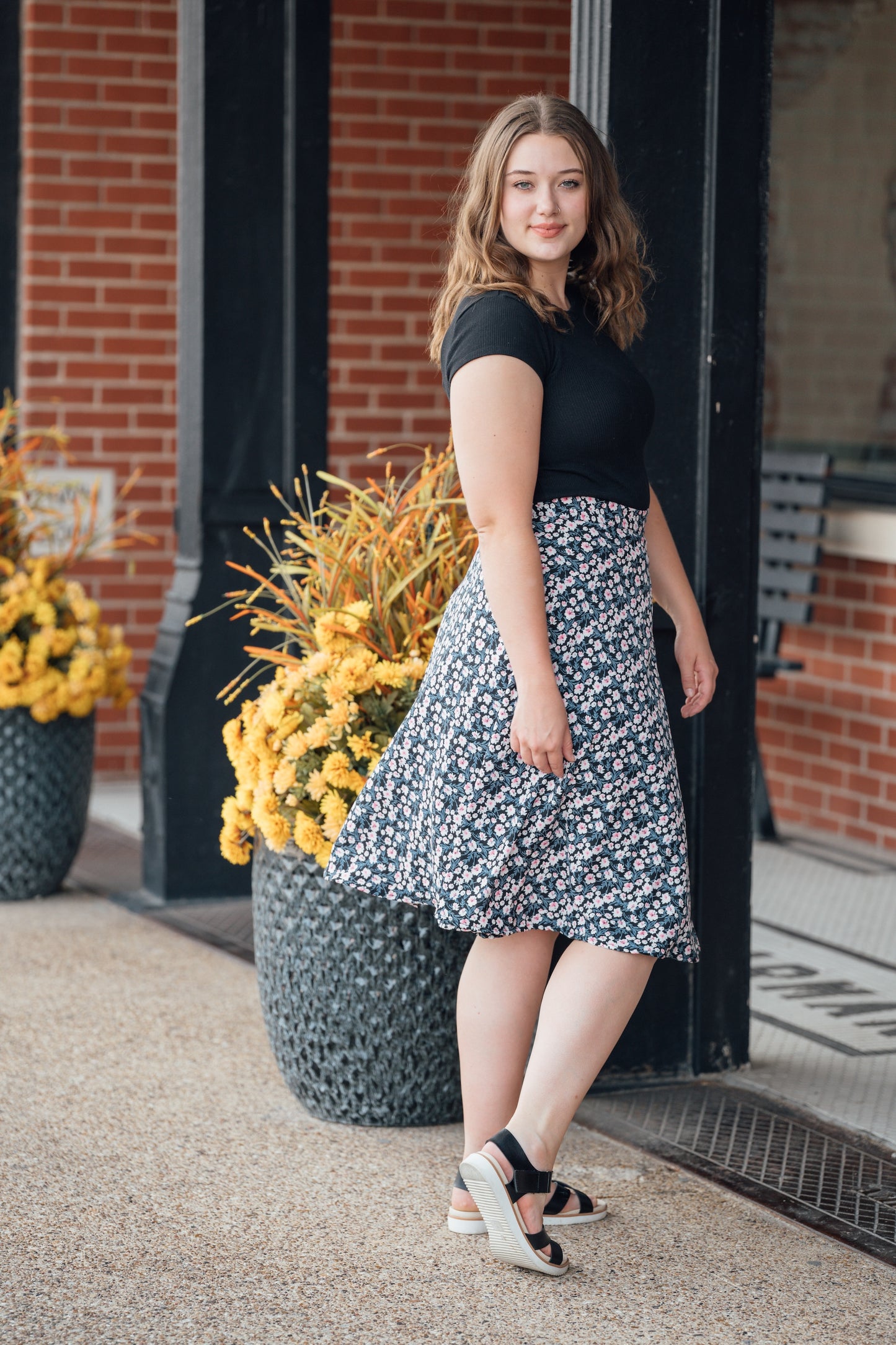 A woman wearing a black midi wrap skirt with pink and white flowers