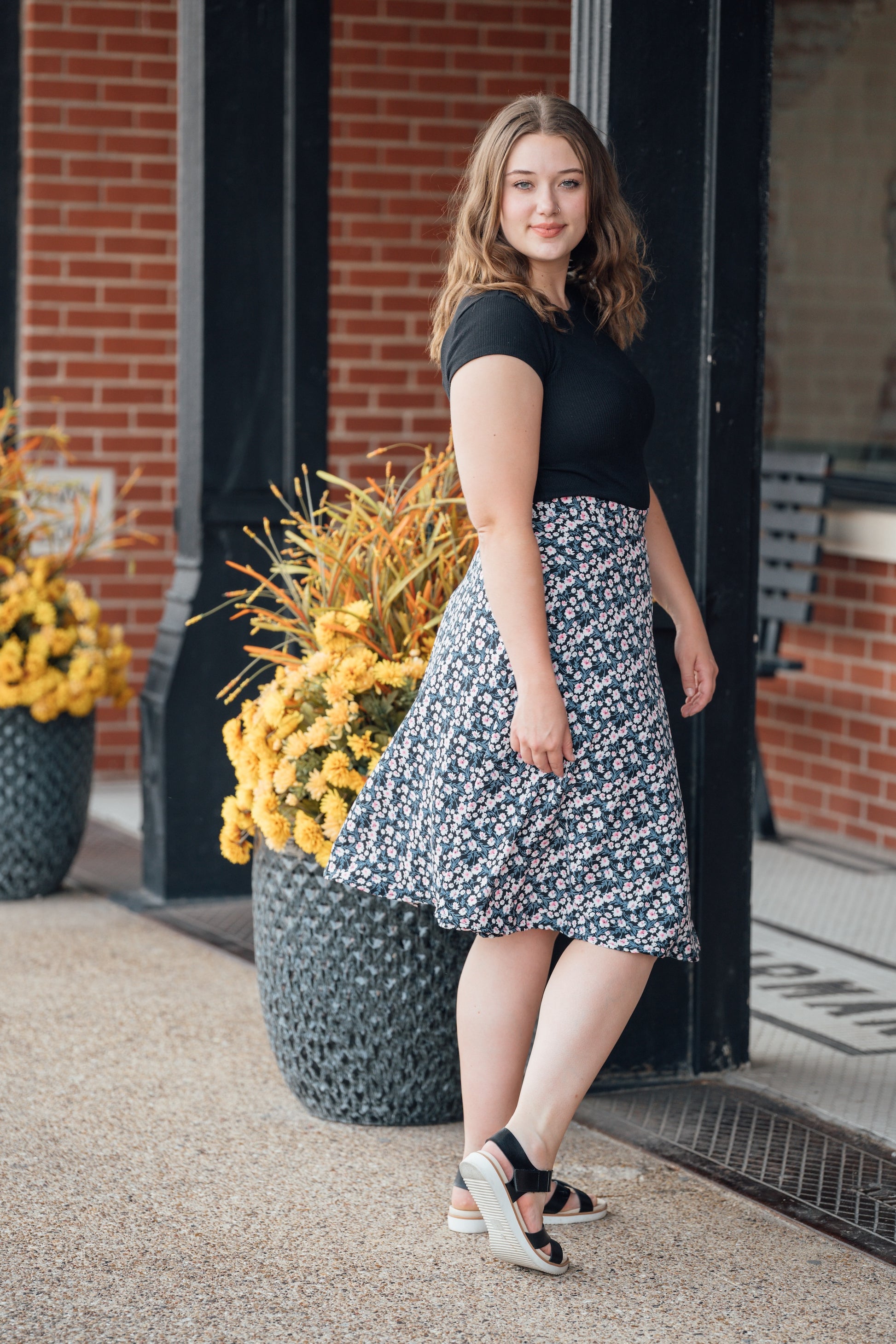 A woman wearing a black midi wrap skirt with pink and white flowers
