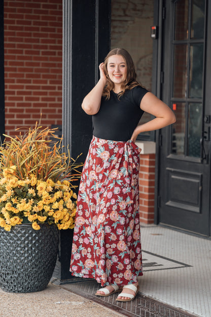 A woman wearing a red maxi wrap skirt with pink flowers
