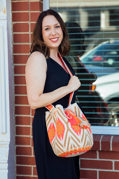 A model wearing a tan, orange, and pink wayuu bag
