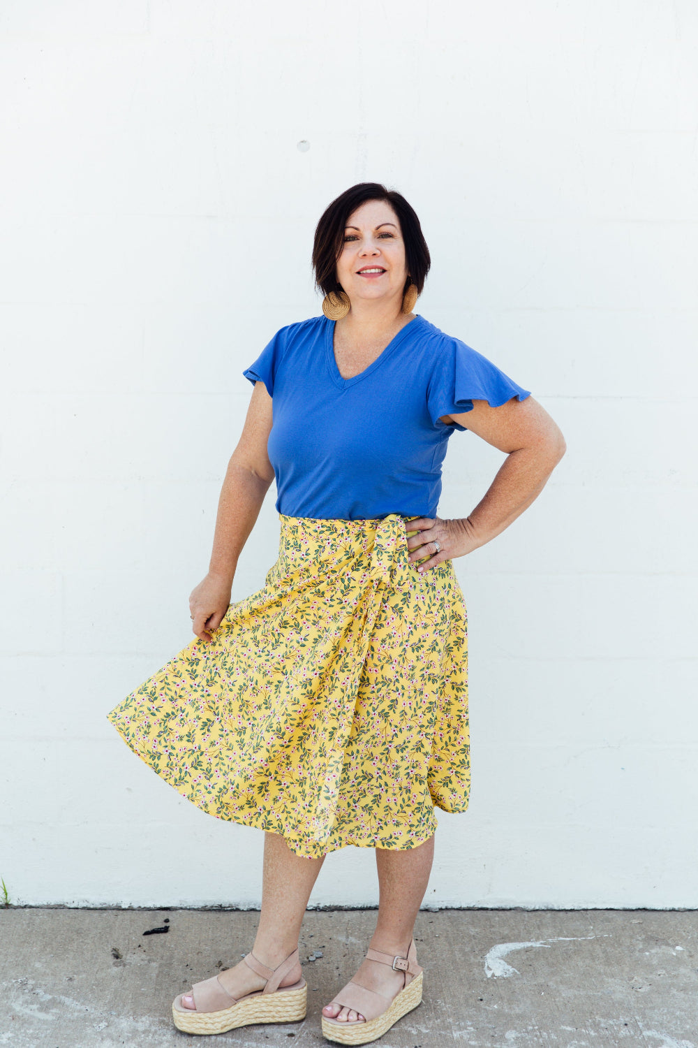 A woman wearing a yellow floral midi wrap skirt 