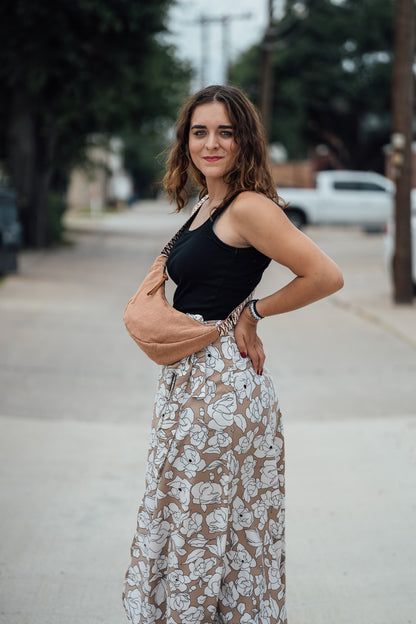 Woman in black tank top and floral skirt holding a Sienna Thai Dumpling Sling Bag on a street.