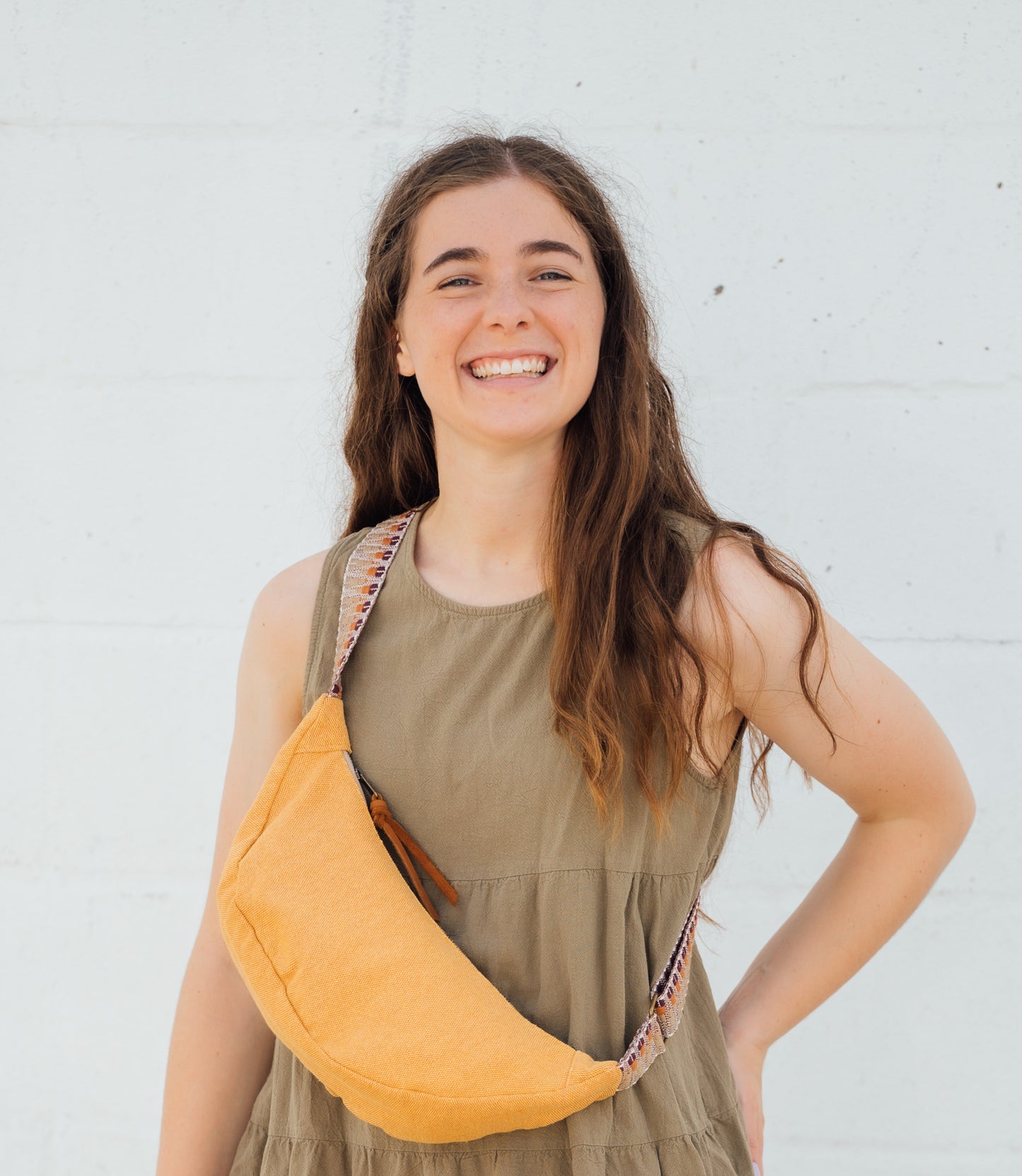 Woman wearing a yellow crossbody bag against a white background