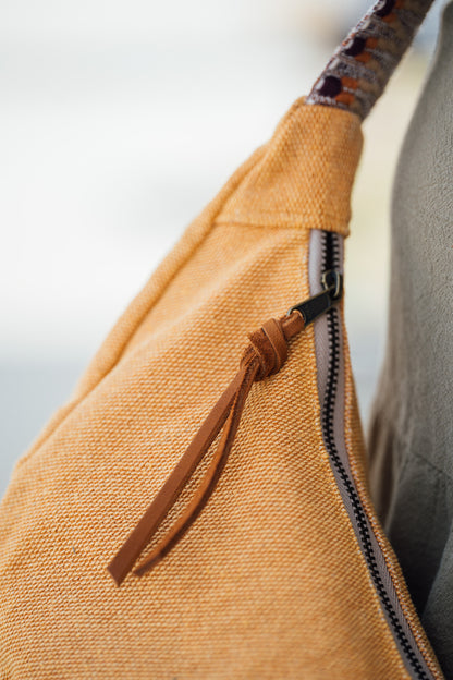 Close-up of a thai yellow dumpling bag with a zipper and woven strap against a blurred background
