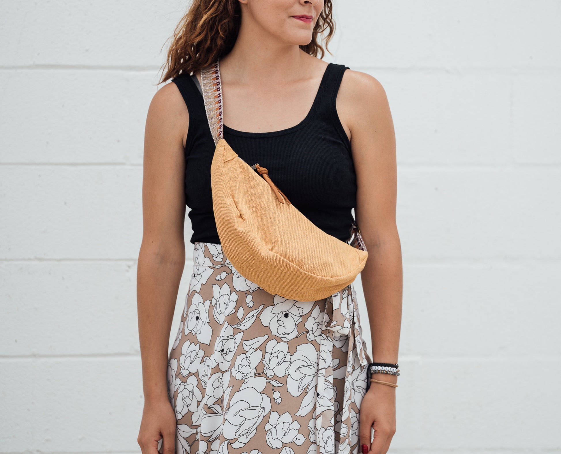 Woman wearing a yellow crossbody bag against a white background