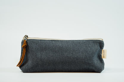 A navy fabric pencil case with a metal zipper and a leather tassel, against a white background.