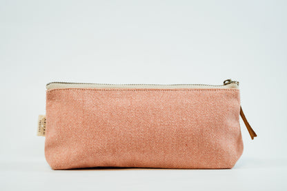 A pink fabric pencil case with a metal zipper and a leather tassel, against a white background.