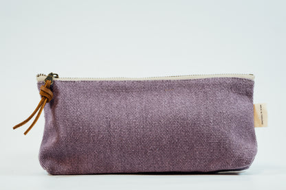 A purple fabric pencil case with a metal zipper and a leather tassel, against a white background.